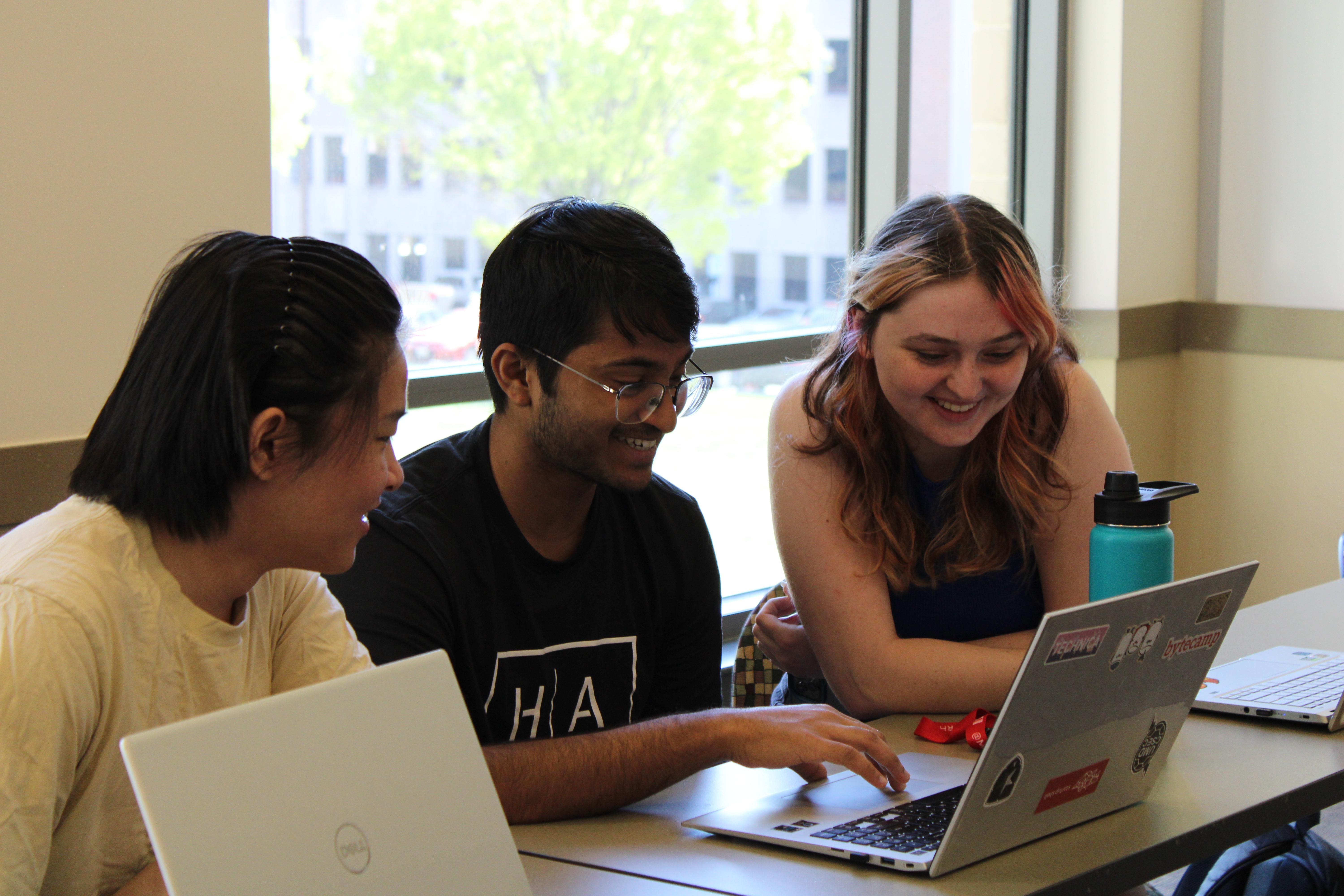 three students looking at a laptop